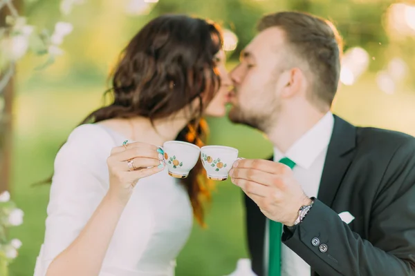 Elegante giovane coppia bacio durante l'ora del tè nel giardino verde — Foto Stock