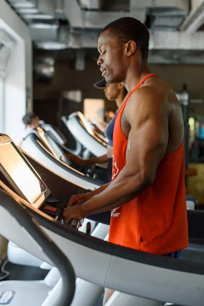 Vue latérale de la formation de bodybuilder noir afro-américain sur le tapis roulant dans la salle de gym — Photo