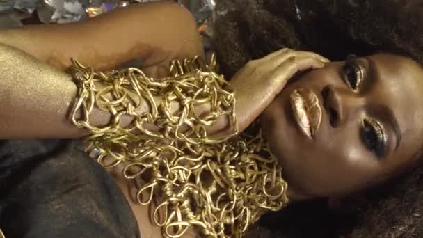 Creatieve surrealistisch portret van sexy Afro-Amerikaanse vrouwelijke model met gouden glanzend make-up gezicht kunst. Zilver glanzend confetti achtergrond — Stockvideo