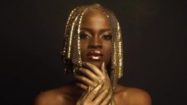 Refleks. Siyah stüdyo arka plan üzerinde poz parlak parlak altın makyaj ile parlak Afrikalı-Amerikalı kadın model portresi. Yüksek moda çekim, Vogue kavramı