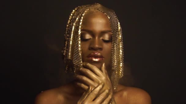 Záhadný kouzelný afroamerický model ženského pohlaví se zlatým lesklým make-upem a s pokrývkou hlavy pro kameru. Vysoký módní koncept Vogue