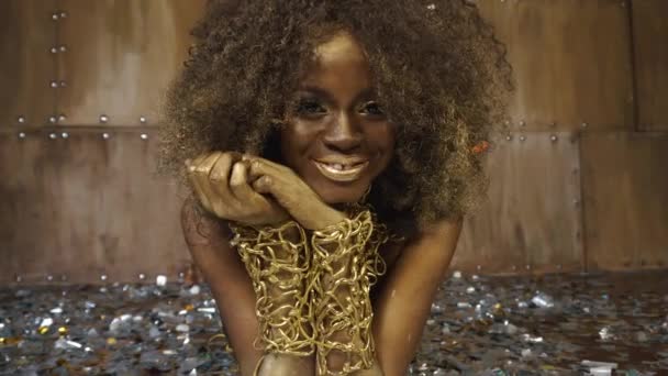 Nahaufnahme Porträt eines sexy afrikanisch-amerikanischen Models mit goldenem Hochglanz-Make-up umgeben von silberfarbener Confettia-Gesichtskunst. Studiohintergrund — Stockvideo