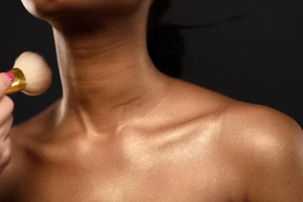 Jonge Afrikaanse vrouw in Studio doen lichaamsverzorging en toepassing van make-up, poeder met een borstel voor mooie huid — Stockfoto