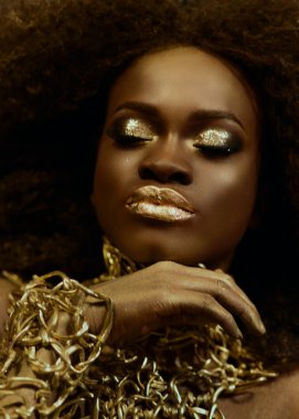 Altın parlak makyaj ile görkemli Afrikalı-Amerikalı kadın modelin yakın çekim gerçeküstü portre. Moda Vogue konsepti