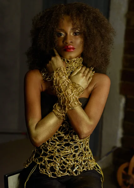 Роскошный портрет сексуальной африканской модели-женщины с глянцевым золотым макияжем, позирующим перед камерой. Бронзовая бодикраска, студийный фон — стоковое фото