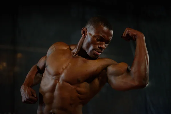 特写肌肉的非洲美国英俊的身体建设者假扮与裸体躯干在黑色工作室背景 — 图库照片