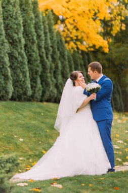 Yeni evli çift yeşil güneşli park selvi ağaçları ile poz