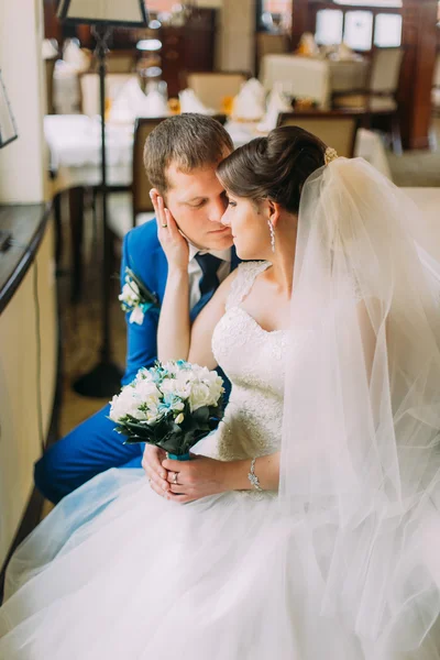 Charming bride in beautiful white dress gently kissing her stylish dressed groom — Stock Photo, Image