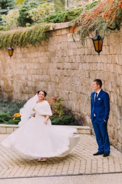 Zarif güzel düğün çift, neşeli gelin kumtaşı duvarının yakınında sevgi dolu damadın dans