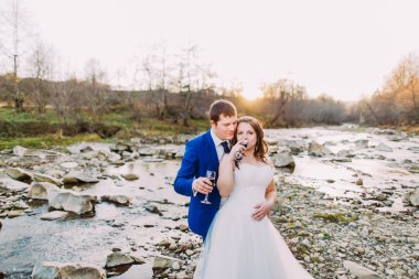 Yeni evli çift romantik kayalık çakıl nehir kıyısı forest hills ve akış ile şarap içme