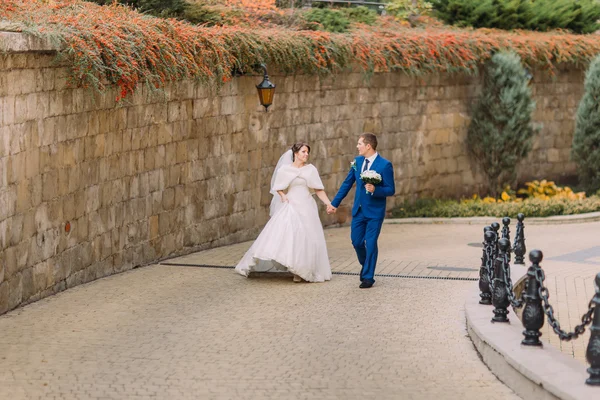 Casal de casamento, noiva alegre e noivo amoroso passeando no parque perto da parede de arenito — Fotografia de Stock