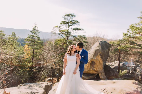 Momento romántico de la pareja recién casada: el novio sostiene suavemente a su nueva esposa de pie sobre la roca —  Fotos de Stock