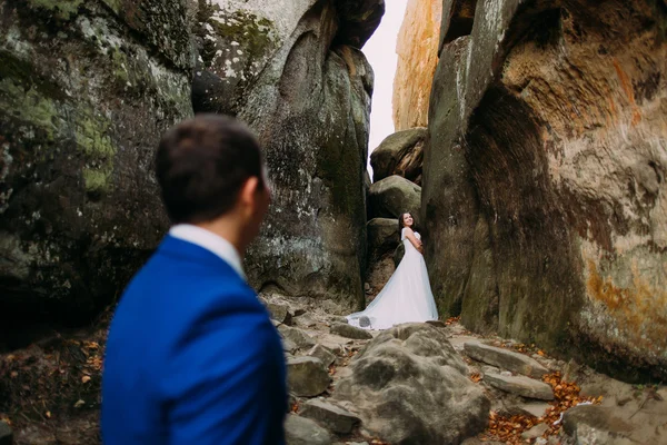 Marié aimé regarder comme sa mariée posant dans la fente rocheuse altérée — Photo