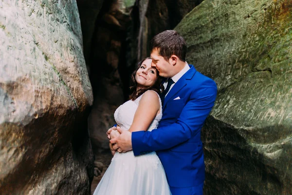 Jeune et romantique couple nouvellement marié posant dans un fond de roche altérée — Photo