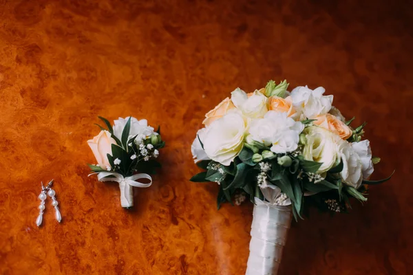 Brincos de noiva, bonito boutonniere e buquê de noiva no fundo de madeira rústica — Fotografia de Stock