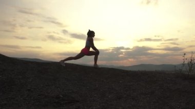 Sunset bulvarında açık germe uygun kaslı kadın silüeti. Fitness kavramı