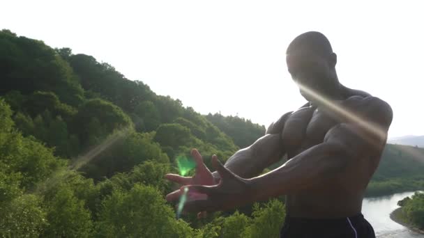 Sterke knappe Afrikaanse Amerikaans bodybuilder is opleiding op de rots in de bergen. Groene woud berg achtergrond — Stockvideo