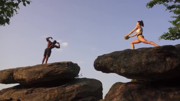 Gemengd ras paar zwarte bodybuilder en Kaukasische fit gespierde vrouw doen oefeningen samen op de rotsachtige piek. Sport gezondheidszorg concept. — Stockvideo