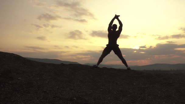 Schoonheid van het menselijk lichaam. African American bodybuilder stretching bij zonsondergang tijdens zijn outdoor opleiding. — Stockvideo