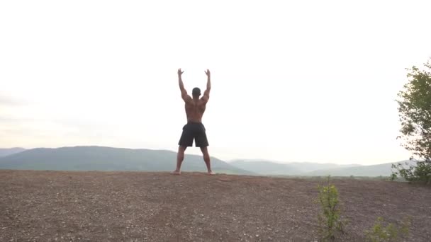 Афроамериканського будівельника тіла з досконалим тілом, що тягнеться на гору пік під час його ранкового тренування на відкритому повітрі. Sunrise Sky фону. Спорт здорова концепція — стокове відео