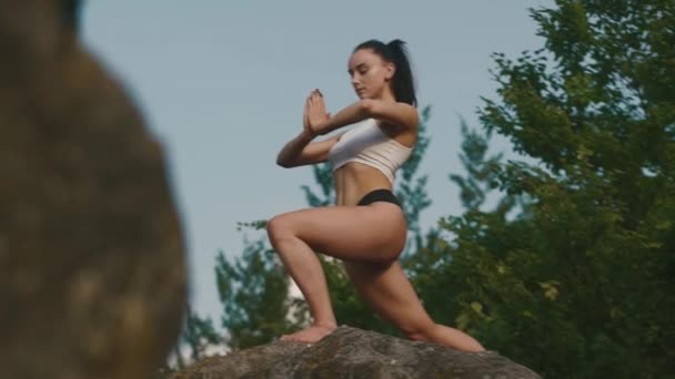 Hermosa mujer morena fuerte practicando yoga al aire libre en el borde del acantilado y relajante. Fondo del cielo nocturno — Vídeo de stock