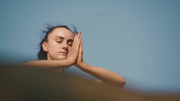 Close-up de mulher morena adorável praticando ioga no pico da montanha rochosa. Céu azul claro fundo — Vídeo de Stock