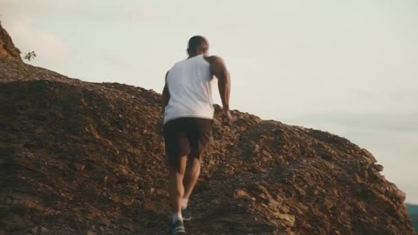 Vissza véve az afroamerikai izmos testépítő jogging kültéri. Sziklás hegyi tájkép háttér — Stock videók