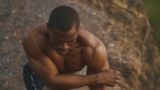 Nahaufnahme eines afrikanisch-amerikanischen Bodybuilders mit nacktem Oberkörper, der sich im Freien dehnt — Stockvideo