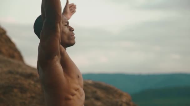 Seitenansicht eines starken afrikanisch-amerikanischen Bodybuilders, der sich im Freien dehnt. Hintergrund Berglandschaft — Stockvideo