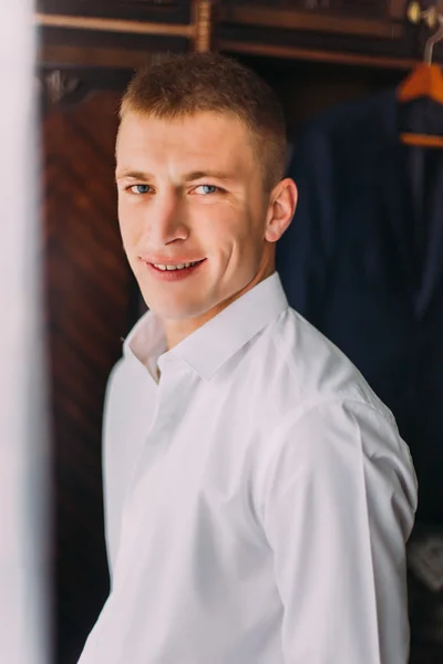 Beau gars élégant regardant la caméra et souriant tout en se tenant debout dans le vestiaire — Photo