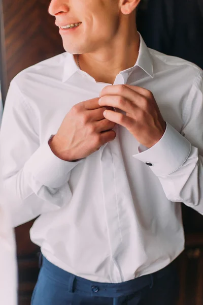 Jovem homem bonito vestindo sua camisa branca no quarto do hotel — Fotografia de Stock