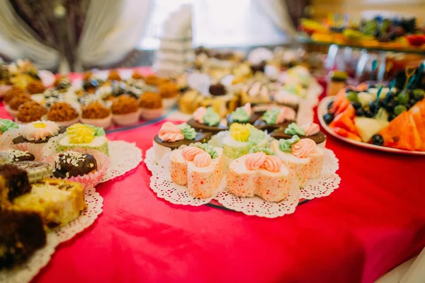 Close-up of fancy served dessert buffet on red tablecloth in luxurious party restaurant setting