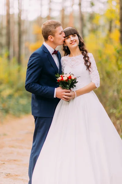 Happy newlywed bride and groom posing in the autumn pine forest — Stock Photo, Image