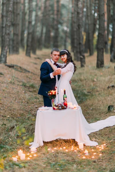 Романтичний осінній сосновий ліс зі свічками. Щаслива молода пара святкує свій шлюб — стокове фото