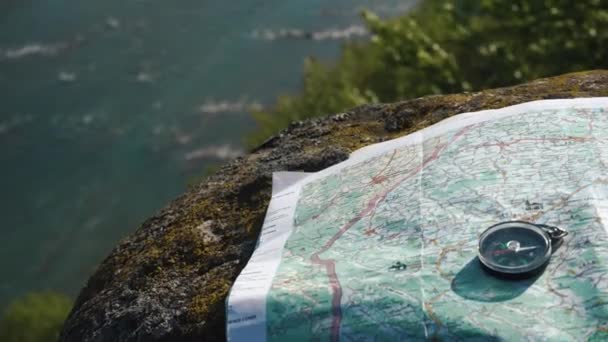 Bússola redonda simples com mapa de terreno de papel na pedra resistida perto de grande fluxo de montanha — Vídeo de Stock