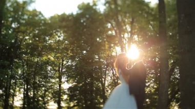 Güzel düğün çift ormanda usulca öpüşme. Güzel gün batımı arka plan üzerinde. Büyüleyici an