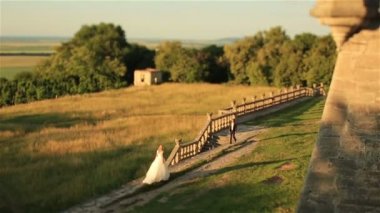 Güzel romantik Düğün çifti, damat ve gelin karşılamak ve sunset bulvarında eski ortaçağ kalesi sarılmak
