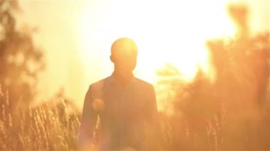 Yakışıklı damat buğday sahada güzel gün batımı sırasında yürüyüş.