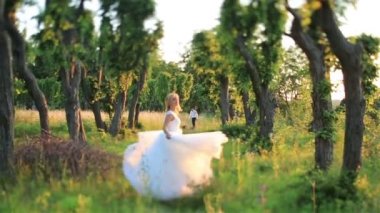 Güneş ışınları tarafından yaktı yeşil bahar ormanda çalışan güzel genç sarışın gelin. Arka plan üzerinde yakışıklı damat