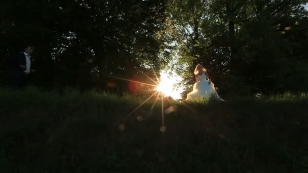 Preciosa novia rubia y novio bailando al aire libre en la luz del atardecer, mirando feliz en su boda — Vídeo de stock