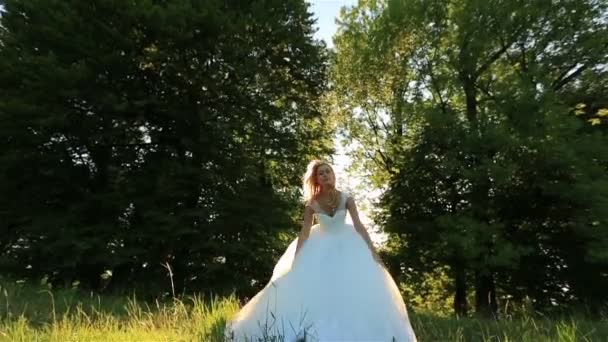 Attrayant jeune mariée blonde sautant et s'amusant dans la prairie verte dans la journée ensoleillée d'été 