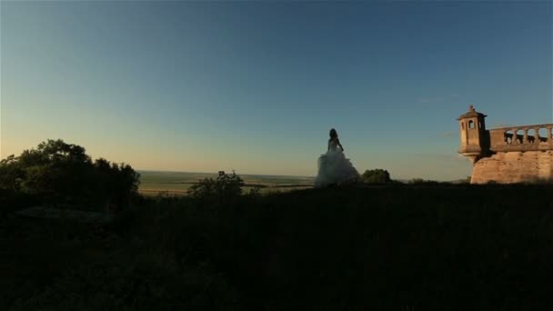 Silhouette of beautiful stylish blonde bride posing near old castle tower — Stock Video