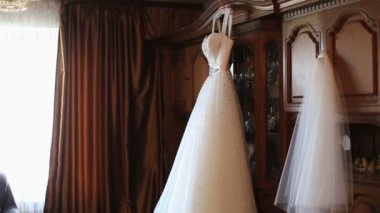 Pencere kenarındaki ahşap raf arka plan üzerinde asılı güzel beyaz gelinlik