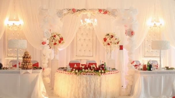 Роскошный свадебный зал в ресторане, украшенный красными и белыми цветами — стоковое видео