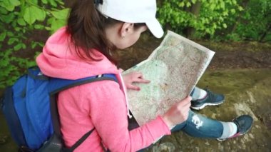 Genç ciddi turist kadın ile onun harita için arıyorum ve yerel arazi ile kontrol gözler yukarı kaldırma sırt çantası