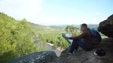 Gölgeli kaya kaya nehir görünümü olumsuz ile otururken harita ile kontrol genç turist adam