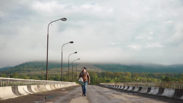 Genç erkek turist dağlarda boş karayolu üzerinde yürürken yolda yol haritası ile kontrol — Stok video