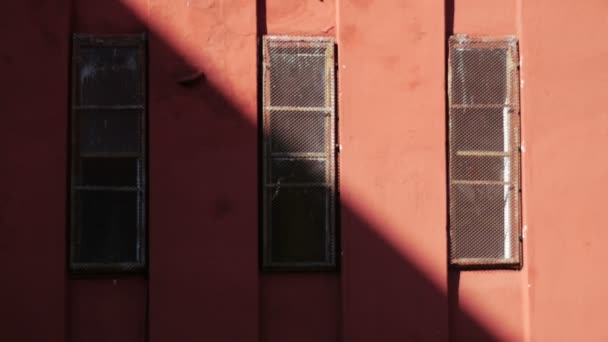 Rote Wand mit seltsamem Mann, der in Fenster schießt — Stockvideo