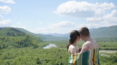 Genç baştan çıkarıcı çıplak çift kaplı battaniye tarafından yumuşak yeşil dağların arka planda embrasing