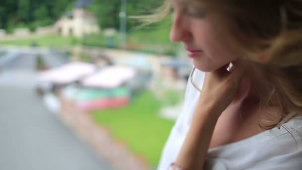Sabahleyin, hafif beyaz bluz büyüleyici genç kadında rahat balkon onun kitap okur — Stok video